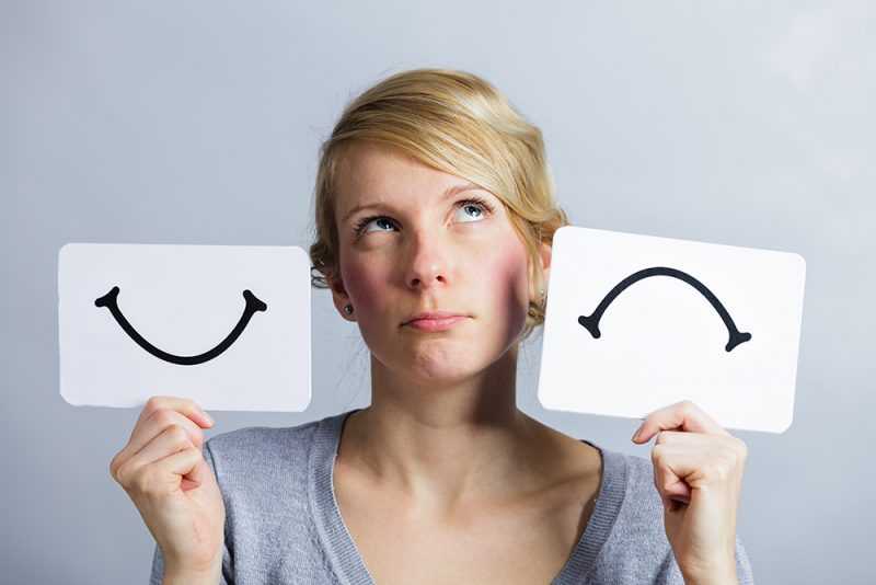 woman holding up smile and frown images